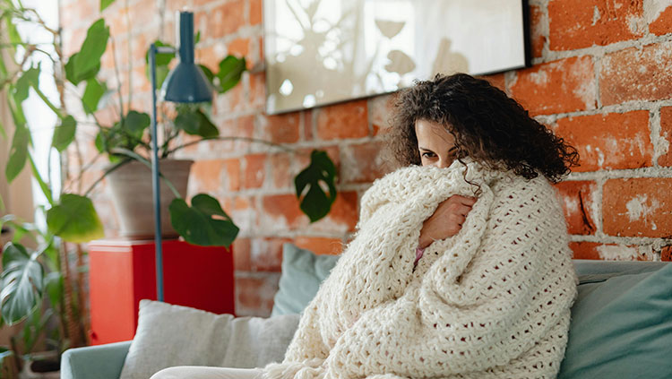Woman sitting on couch with blanket