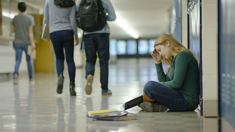 Teen sitting on floor by lockers
